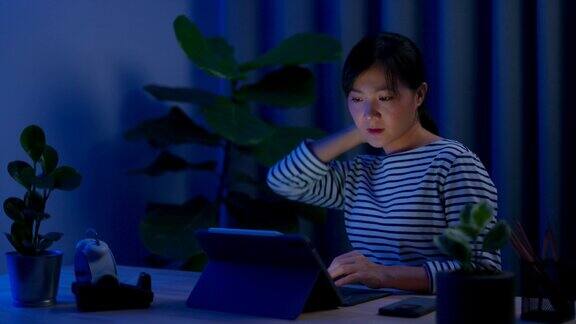 亚洲女性晚上在家里办公室用笔记本电脑工作身体疼痛