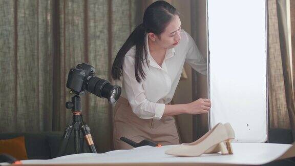 亚洲女摄影师在家庭工作室拍摄产品时调整灯光设备以使女性鞋子获得良好的照明