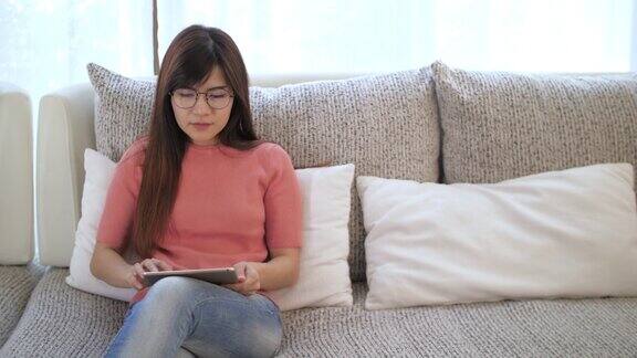 年轻女子周末在家放松在客厅沙发上使用平板电脑