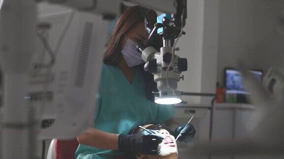 亚洲华裔女牙医在牙医办公室里用显微镜观察病人的牙齿