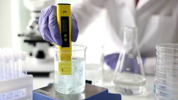 化学家在实验室近距离4k电影慢动作中使用pH计测量玻璃中液体的酸度