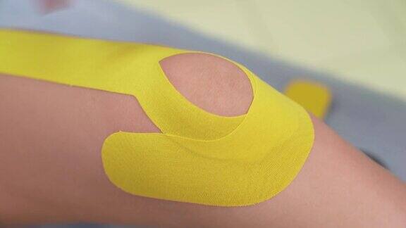 一个专业理疗师在病人膝盖上固定运动胶带的特写演示视频