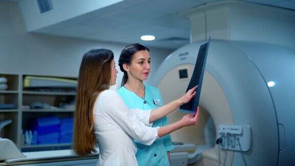 女医生和护士在看x光照片两位专家在临床分析现代医疗设备背景下的x线照片