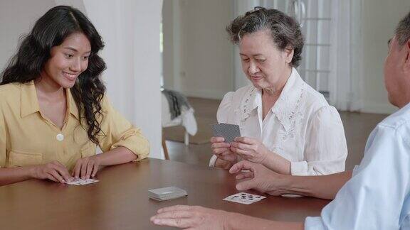 快乐的亚洲家庭女儿和爸爸妈妈在度假时在家里的木桌上玩纸牌游戏快乐的家庭理念