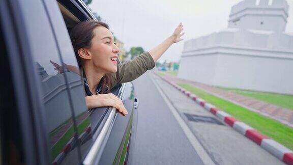 亚洲美女旅行者打开车窗面对外面的空气有魅力的年轻女游客背包旅行在美丽的城市花时间自驾游在泰国的假期旅行