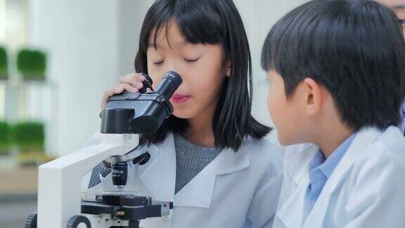 教师和好奇的学生在实验室利用显微镜进行科学实验