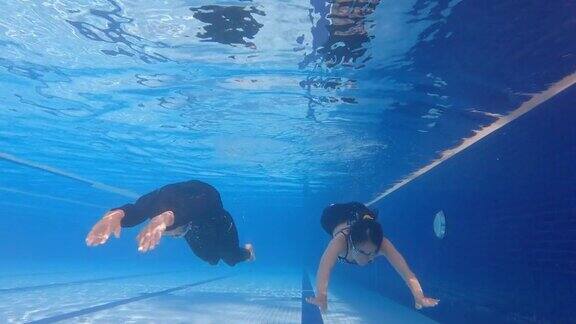 亚洲华人夫妇一起在游泳池水下游泳