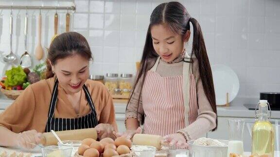 年轻的母亲和小女孩在厨房准备食物做饭