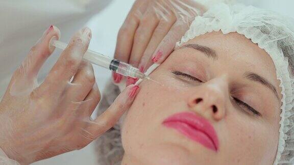 现代美容诊所的美容注射过程特写用注射器注射至女性面颊美容院美容师进行美容及拉皮治疗
