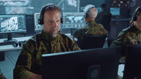 军事监视团队的军官戴着耳机工作在一个中央办公室枢纽为网络行动控制和监控管理国家安全技术和军队通信