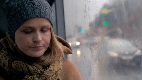 在一个沉闷的雨天公交车上的一个悲伤的年轻女人