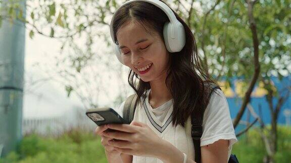 微笑的女人用智能手机和耳机拥抱大自然的旋律