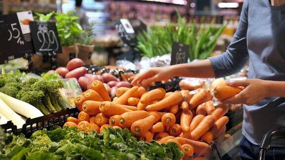 漂亮的女人在超市买胡萝卜蔬菜和水果