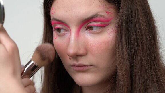 模特用化妆刷在脸上涂粉底化妆后照镜子