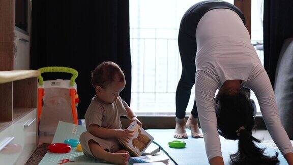忙碌的妈妈在瑜伽上被宝宝打断的镜头