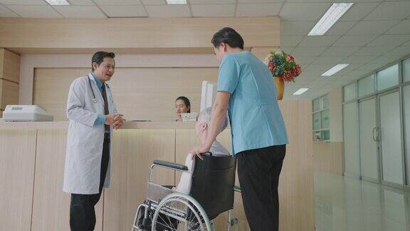男护理助理坐在轮椅上关心地与病人交谈在医院或诊所