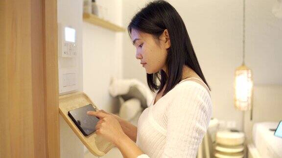 亚洲女性用家庭自动化和智能家居技术开空调、灯和空调
