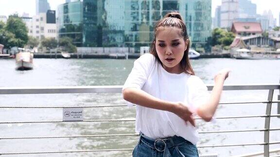 年轻女子在河边跳街舞作为背景亚洲的女人中景镜头
