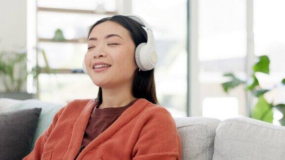 音乐音频和女人放松听一首歌在家里坐在沙发或沙发享受收音机在公寓里快乐快乐和年轻人在客厅里玩耳机