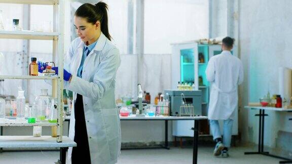 研究概念和生物化学科学家女和她的助手男一起在玻璃桶里混合一些化学液体来做实验