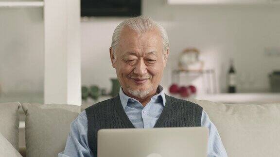亚洲老人在家里使用笔记本电脑