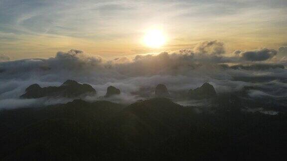 在日出时与雾流一起飞越局部山脉航拍视频