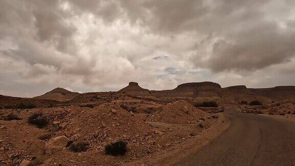 在阴天驾车沿着沙漠公路前往突尼斯的KsarGuermessa穴居人村庄司机的观点