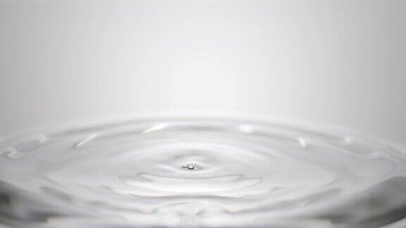 灰色的水滴落在清澈的液体表面形成圆圈