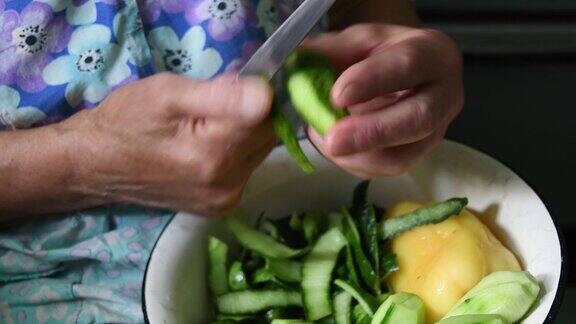 特写:一位年长女性用刀削黄瓜皮手起皱纹