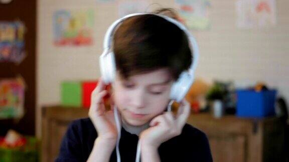 一个可爱的小男孩戴着耳机听音乐的肖像