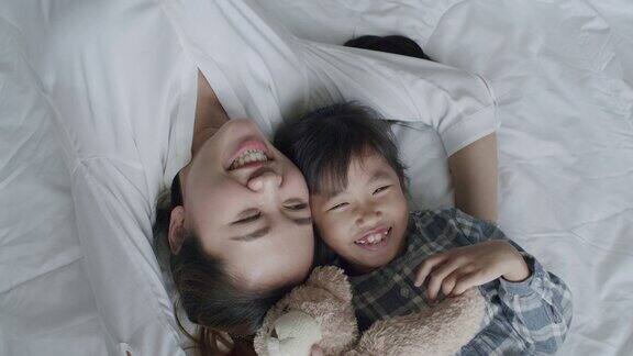 前视图家庭快乐的亚洲母亲和女儿在早上躺在床上看着相机