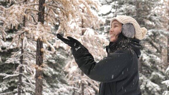 亚洲女人在冬天的森林里享受降雪