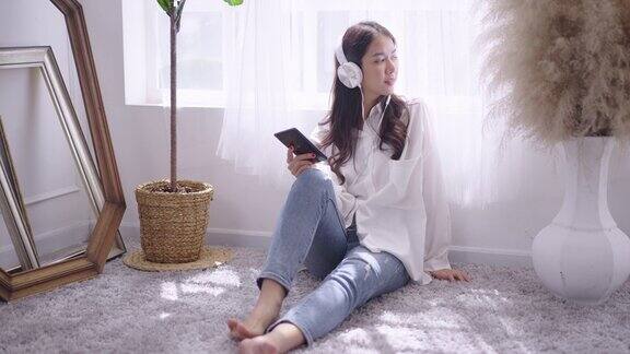 年轻的亚洲女性在家里用智能手机听音乐