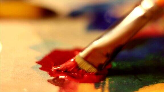 艺术家用红色颜料降低画笔并在调色板上混合它