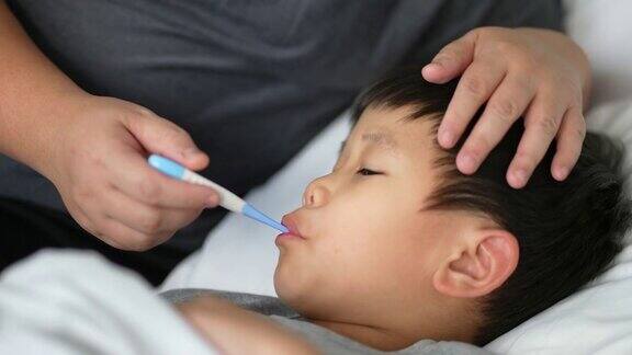 亚洲孩子感到恶心的温度计和母亲照顾和生病