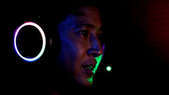 近距离认真的亚洲电子竞技玩家玩视频游戏与他的耳机