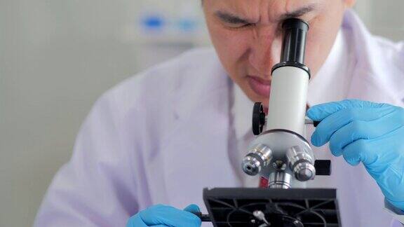 在生命科学实验室工作的卫生保健研究人员年轻男性研究科学家在实验室准备和分析显微镜载玻片科学实验室