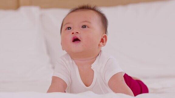 新生婴儿平躺在床上发展颈部控制腹部时间加强婴儿颈部和肩部肌肉可爱的婴儿躺在白色的床上爬行幸福和乐趣肚子上的时间
