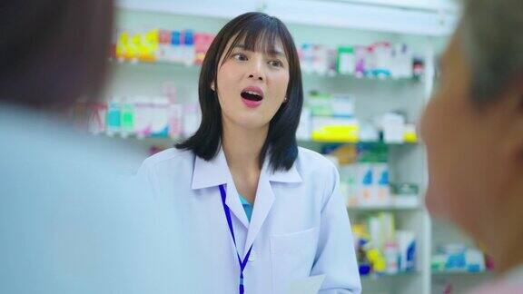 年轻的亚洲药剂师在药房柜台与顾客交谈
