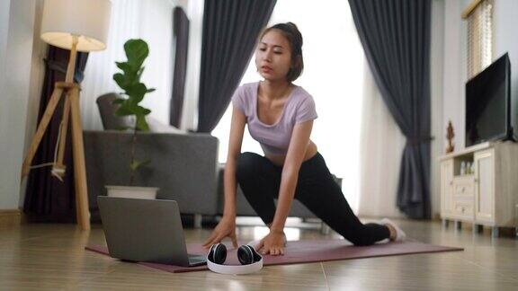 年轻的肌肉健身女性在家里客厅地板上的瑜伽垫上做运动和瑜伽