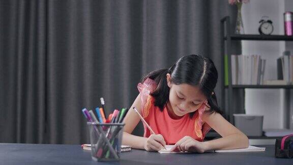 亚洲小女孩学习科学和在书上写笔记而呆在家里自主学习在线学习她正在用铅笔写家庭作业