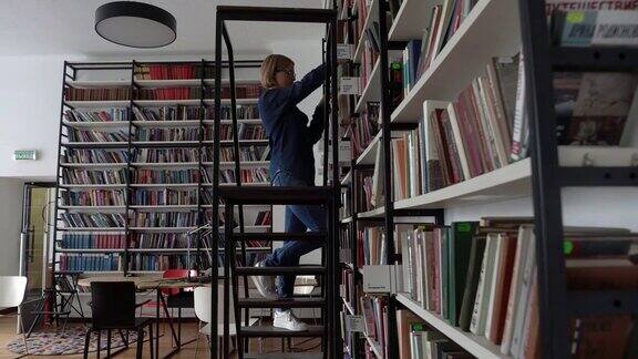 年轻漂亮的女学生在图书馆走上楼去取图书馆的一本书
