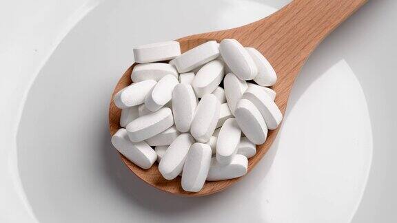 陶瓷背景木勺里的白色药片旋转医疗保健