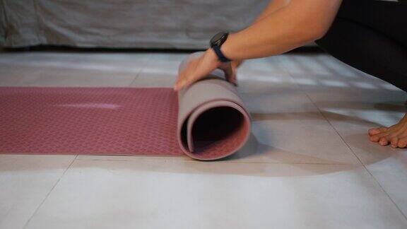 近距离卷起瑜伽垫在家里的客厅锻炼
