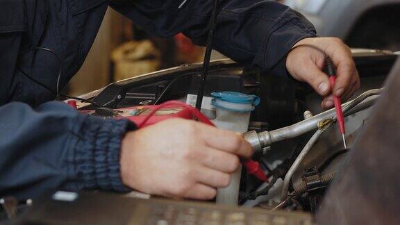人们用万用表测量电池的电压做汽车检查的机械师正在用测试仪测试汽车电池用万用表检查电池电压