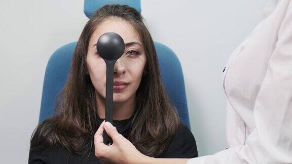 细心的验光师检查一位美丽的女病人在眼科诊所用一个闭塞器检查她的视力现代诊所的检查病人的特写正面
