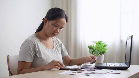 压力大的亚洲年轻女性管理财务和信用卡账单在家里用手机计算家庭财务债务一个做开支计划的妻子