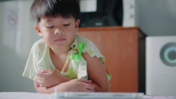 亚洲小男孩在医院用平板电脑看电视