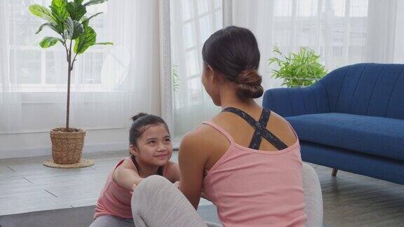 母亲正在家里教女儿伸展身体瑜伽锻炼