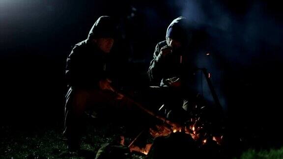 两个朋友晚上坐在篝火旁聊天